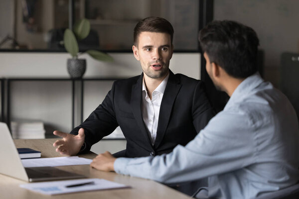 Два бизнесмена обсуждают сделку или продвижение проекта, обсуждают условия контракта, планируют дальнейшее сотрудничество или бизнес-возможности, анализируют данные маркетинговых исследований, встречающиеся в офисе компании с ноутбуком