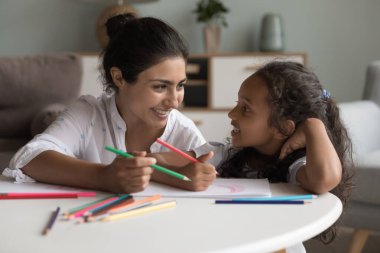 Neşeli, güzel Hintli bir anne ve tatlı küçük bir kız çocuğu evdeki masalarda renkli kalemler çiziyor, konuşuyor, sohbet ediyor, kağıda renkli karalamaları tartışıyor, gülüyor, eğleniyor.