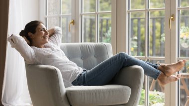 Neşeli, tasasız, güzel bir Hintli kadın büyük teras penceresinde rahat koltukta dinleniyor, tembellik ediyor, mutlu, derin bir nefes alıyor, keyfine bakıyor, evinde rahat ediyor. Sancak vuruşu