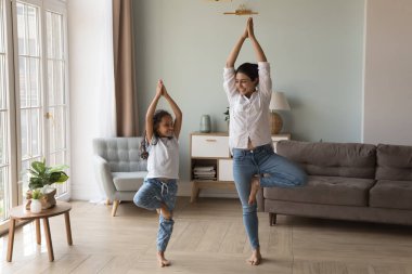 Mutlu Hintli Yogi annesi kızına yoga yapmayı öğretiyor, ağaç duruşu yapıyor, gülümsüyor, gülüyor, konuşuyor, ev egzersizlerinden zevk alıyor, boş zamanlarında eğleniyor, sağlıklı yaşam tarzını koruyor.