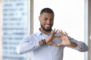 Göğsünde el yapımı mutlu, yakışıklı genç bir adam. Blogcu, aşkın romantik sembolünü gösteren, Sevgililer Günü 'nde dişlek bir gülümsemeyle kameraya bakan. Kapalı erkek portresi