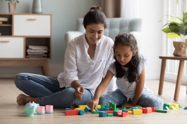 Neşeli, güzel Hintli anne ve küçük kız evdeki ısıtma tabanında oynuyorlar renkli oyuncak blokları düzenliyorlar. Dadı, kreş öğretmeni çocuğu eğlendiriyor, öğrenme oyununun keyfini çıkarıyor.