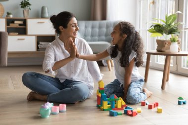 Mutlu Hintli anne ve güzel küçük kız el çırpıyor, ahşap yapı taşları, oyuncak kulesi, ısıtma odasındaki şato, model tamamlama kutlamaları için beşlik çakıyor.