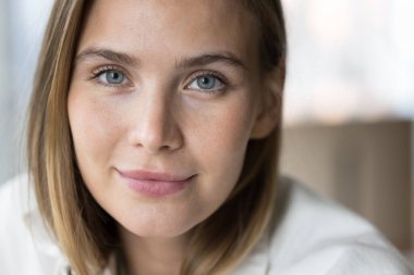 Genç ve güzel bir kadının, gülümseyen, kameraya bakan görüntülerini yakın çekim. Çekici görünüşlü ve mükemmel ciltli muhteşem bir kuşak kadın portresi. Kozmetik, doğal güzellik