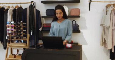 Küçük işletme sahibi portresi, modern butik mağaza çalışanı tezgahta duruyor ve dizüstü bilgisayarda çalışıyor, operasyonel ya da idari görevlerle uğraşıyor, kameraya poz veriyor. Girişimcilik, yönetim