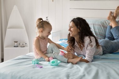 Çocuk gelişimi konusunda rol yapma oyunu. Gülümseyen genç anne, küçük tatlı anaokulu kızıyla boş vakitlerini büyük bir yatak tutarak hayali çay eşliğinde sohbet ederek geçirir. Boşluğu kopyala