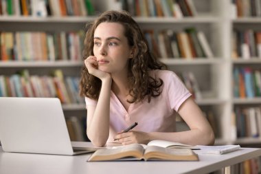 Öğrenmek zordur. Düşünceli ergen genç bilim kadını öğrenci kütüphane masasında oturuyor. Not defterinin yanında. Kalem tutucu.