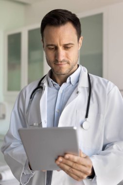 Odaklanmış doktor hasta kayıtlarını, geçmişlerini, elektronik randevu çizelgesini, tıbbi uygulamayı, tablet bilgisayardaki servisi, cihazları, daktiloyu, interneti kontrol ediyor.