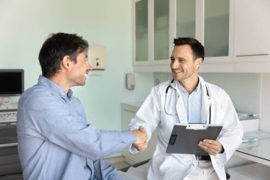 Mutlu doktor ve hasta muayeneden sonra hastane ofisinde el sıkışıyor. Tıbbi uzman, mutlu bir adamla tokalaşıyor. Başarılı bir tedaviden sonra iyi haberler veriyor.