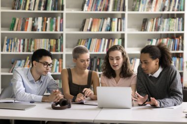 Teknik ve çalışma. Üniversite kütüphanesinde dizüstü bilgisayar kullanan dört farklı çok kültürlü okul arkadaşı video konferans bilgileri online kaynaktaki bilimsel makaleyi tartışır