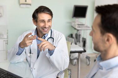 Pozitif orta yaşlı Latin doktor hastane ofisindeki iş yerinde erkek hastayla konuşuyor, teşhisi açıklıyor, danışmanlık yapıyor, konuşuyor, gülümsüyor.