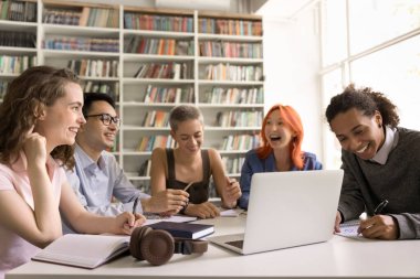 Uzaktan eğitim. Mutlu arkadaş canlısı polyetik grup öğrencileri halk kütüphanesinde uzaktan öğreniyorlar sanal sınıfa bilgisayar uygulaması gülüşü kullanarak el yazısı konferanslarına katılıyorlar