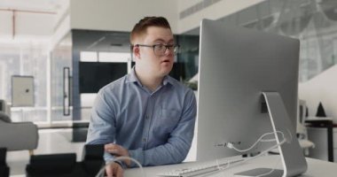Ofiste çalışan PC kullanan Down sendromlu bir adam, verileri hesap tablolarında organize eder, analiz eder, programları yönetir, e-postalara cevap verir, ya da belge ve raporlar hazırlar, bilgi için interneti tarar.