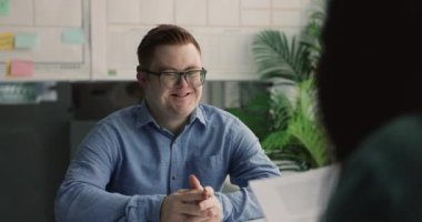 Özürlü, Down sendromlu genç bir adam iş görüşmesinde geçiyor, soruları cevaplıyor, mesleki beceriler, eğitim ve yetenekler hakkında konuşuyor. İnsan kaynakları, kapsayıcılık, adam toplama