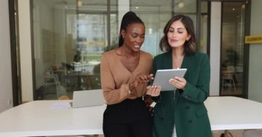 Tablet kullanan çok ırklı kadınlar, modern konferans odasında yeni program veya yazılım tartışmaları, ortak görev veya sunum hazırlama, ofiste verimli bir takım çalışması stratejisi geliştirme