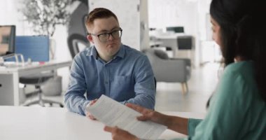 Konuşan genç bayan, Down sendromlu adama iş sözleşmesi detaylarını açıklayın, toplantıyı bitirin ya da iş görüşmesini el sıkışarak saygıyla yapın. Pazarlıklar, ortaklık anlaşması, anlaşma