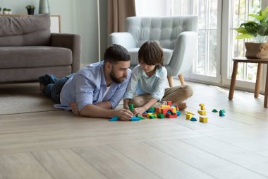 Sevgi dolu baba ve oğul tahta bloklar oynar. Anaokulu çocuğu, renkli küpleri modern evde babasıyla vakit geçirmek için kullanır. Çocuklar için oyunlar, gelişim oyuncakları mağazası reklam konsepti