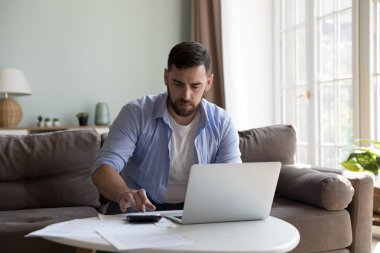 Ciddi milenyum adamı kanepeye oturur, evrak işleri yapar, vergilerini öder ve elektronik banka uygulamasını kullanır, bütçeyi yönetir, tasarrufları planlar, yatırımlar odaklanmış görünür. Mali konsept
