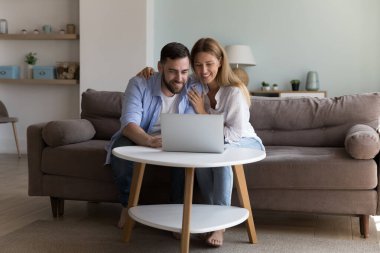 Çift kanepede dizüstü bilgisayarla mal alıyor, uzaktan sipariş veriyor, kolay perakende satış hizmetlerinin keyfini çıkarıyor rahat yaşam için internet kullanıyor. Modern teknoloji, otel rezervasyonu, aile tatillerini online planlama.