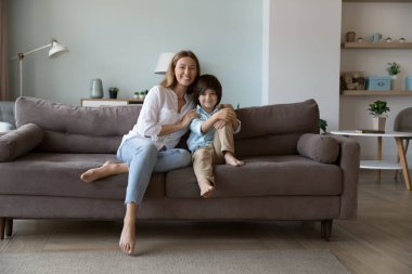 Genç, güzel bir anne kameraya poz veren oğluna sarılıyor kanepede oturuyor, hafta sonları evde birlikte vakit geçirip arkadaşça ilişkiler kuruyor. Mutlu annelik, velayet, aile bağları ve bağlılık