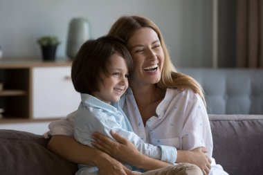 Mutlu genç kadın, anaokulundaki 6 yaşındaki oğluna sarılıyor. Sevgi dolu bir anne, sevimli bir çocukla vakit geçirir. Kanepeye oturur, çok mutlu görünür, evde boş vakitlerin tadını çıkarır, bağlanır, sevgi hisseder. Annelik kavramı