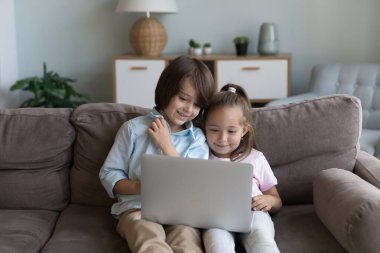 Anaokulu çocukları kanepede dizüstü bilgisayarlarıyla oturur, favori video bloğunun tadını çıkarır, çizgi filmlerin modern kablosuz teknolojiyi kullanmasını izlerler. Gencin aşırı kullanımı, ebeveyn denetim yazılımı kavramı
