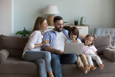 Genç çift ve kardeşler kanepede oturur, internette bilgisayar kullanarak vakit geçirir, internette en sevdikleri videoyu izler, evde dinlenirler. Çocuk gelişimi, modern teknoloji, e-alışveriş, düzen konsepti