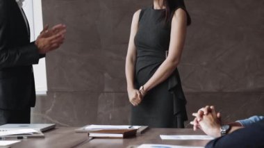 Kırpılmış manzaralı mutlu takım arkadaşları alkışlıyor, yeni kadın çalışanı selamlıyor, ofis konferans odasında grup toplantısında iş başarısı gösteren bayan meslektaşlarını tebrik ediyor. Onaylama, tanıma