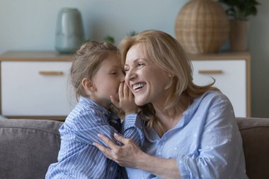 Şirin küçük kız kulağına fısıldıyor ve neşeli büyükannene sırrını söylüyor. Mutlu orta yaşlı kadın torunu dostça ilişkilerinin, güven ve anlayışlarının keyfini çıkarıyor, evde konuşuyor, birlikte vakit geçiriyor.
