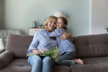 Mutlu orta yaşlı büyükanneler çiçek alır. Sevgi dolu küçük torununun doğum gününün tadını çıkar. Kameraya bak. Çok nesilli aile sevgisi ve bağı, yaşam olayları kutlaması