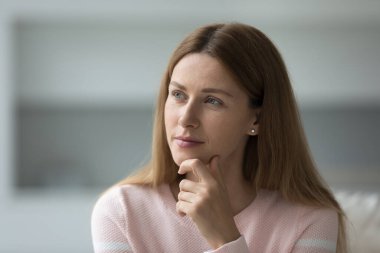 Güzel, düşünceli bir kadın evdeki kanepeye bakar, çenesine dokunur, hayal kurar evde tek başına vakit geçirir, soru üzerine kafa yorar, modern daireyi yansıtır, dinlenir, fotokopi çeker, kafa resmi çektirir.