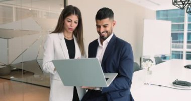 Sunum odasında dizüstü bilgisayar kullanan, online proje içeriğini tartışan, gülümseyen, gülen, ekrana bakan, kablosuz internet teknolojisini takım çalışması için kullanan iki mutlu çok ırklı meslektaşım.