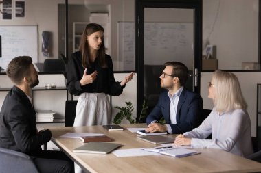 İş kadını, ortak projenin, işbirliğinin, ortaklığın, anlaşmanın sonuçlandırılmasının planlanması için modern konferans salonunda toplanan hissedarların önünde duran bilgileri sağlıyor.