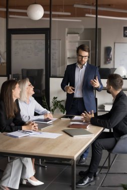 Konferans masasında oturan, hissedarlarla resmi görüşmeler yapan, planlayan, müşteri için ticari teklifte bulunan iş adamı.