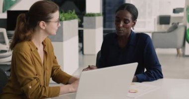 İki kadın takım arkadaşı masada dizüstü bilgisayar ve çizelgelerle birlikte otururken, başlıca tartışma istatistiksel verileri, planlama projesinin tamamlanması, ortak bir görev üzerinde çalışmak ofiste bir araya geldi. Takım çalışması, işbirliği