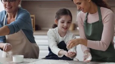 Kırpılmış manzarayı kapat, mutlu kadınlar mutfakta hamur işi pişirir, eğlenir, birlikte pişirir, hamur hazırlar, el çırpar, beyaz un serper, güler, evde aile yemeklerinden zevk alır.