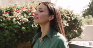 Kadın derin nefes alır ve açık havada canlı çalılara karşı ayakta durur gözleri kapalı, ciğerlerini temiz havayla doldurur sükunet, yenilenme, uyum ve canlılık yayar.