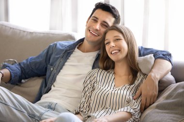 Mutlu, genç, tatlı, Latin bir çift rahat koltukta sarılıyor, başka yere bakıyor, gülümsüyor, gülüyor, TV 'de romantik film seyrediyor, evde dinleniyor, eğleniyor, flört ediyor.