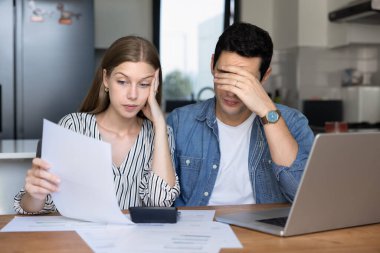 Endişeli genç kiracılar, kiracılar evde çok yüksek kağıt faturaları kontrol ediyorlar, dizüstü bilgisayar başında oturuyorlar, hesap makinesi, harcamaları sayıyorlar, para kaybını düşünüyorlar, iflas riskini düşünüyorlar.