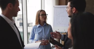 Genç Avrupa takım liderinin başkanlığındaki brifinge dört çok uluslu olumlu takım arkadaşı katılıyor, bilgi sağlıyor, fikir paylaşıyor veya modern ofis yönetim kurulunda bir arada duruyorlar. Takım çalışması.