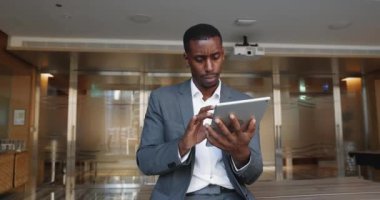 Odaklanmış Afrikalı profesyonel işadamı tablet kullanır, başlangıç için görsel grafikler veya grafikler oluşturur, pazarlama stratejisi geliştirir, beyin fırtınası fikirleri geliştirir veya önemli notlar alır, yeni iş yapay zekası platformlarını keşfeder