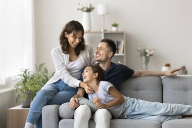 Sevgi dolu ebeveynler tatlı kızlarıyla vakit geçirir, eğlenir, güler, koşulsuz sevgiyi hisseder, evdeki rahat kanepeye oturur, gıdıklanır, iletişimin tadını çıkarır ve onların iyi, ahenkli ilişkilerinin
