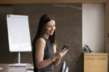 Ofiste akıllı telefon kullanan, mesajları paylaşan, işle ilgili meseleleri uzaktan çözen uygulamayla müşteriye e-posta yazan, yeni platform veya yazılım öğrenen çekici genç bir iş kadını. Modern teknoloji, iş