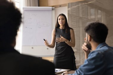 Kadın işletme eğitmeni performans sergiliyor, flip chart sunumu yapıyor, iş stratejisini veya yıllık performans değerlendirmesini paylaşıyor, gelecekteki hedefleri ve yeni hedefleri anlatıyor. Pazarlama kampanyası, seminer
