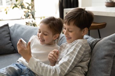 Neşeli Z jenerasyonu çocukları birlikte akıllı telefon kullanarak, sanal video oyunu oynayarak, komik filmler izleyerek, video konuşarak heyecanlandırıyor. Küçük kardeş cep telefonunda küçük kardeş uygulaması gösteriyor.