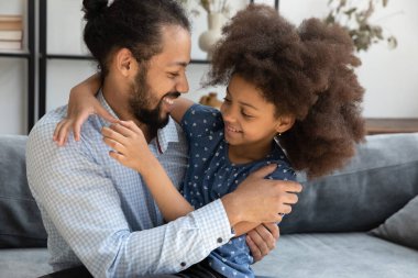 Mutlu, genç, dindar, genç, Afrikalı kızı kucaklayan, kucağında çocuğu kucağına alan, sevgi, ilgi, şefkat dolu, ailevi boş zamanlarından, babalıktan zevk alan genç bir baba.