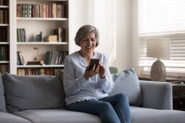 Neşeli son sınıf akıllı telefon kullanıcısı kadın görüntülü konuşma yapıyor, iyi haberlerle mesaj okuyor, gülüyor. Cep telefonunda internet uygulaması kullanan olgun bir kadın. Alışveriş, indirim, kâr.