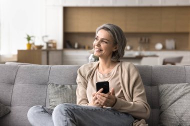 Duygusal bir ruh hali. Hayalperest orta yaşlı kadın rahat ev içi telefon kulübesinde dinleniyor. Bir kenara bak. Dijital fotoğraf videosundaki tatlı anıları yansıt.