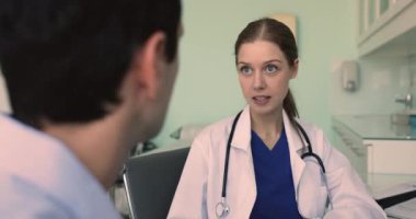 Kendine güvenen, genç, profesyonel bir kadın. Geçmişi kesik erkek hastayla konuşuyor. Tedavi tavsiyelerini açıklıyor, danışmanlık yapıyor, konuşuyor, gülüyor.
