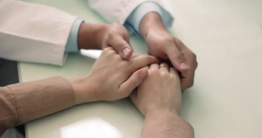 Şefkatli erkek doktor masanın üzerinde genç bir bayanın elini tutuyor, ciddi hastalığı olan bir kadını sakinleştiriyor, teşhis koyuyor, destek oluyor, sempati duyuyor, tıbbi tavsiye veriyor. Silahları kapatın.